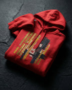 Team Red Tares hoodie folded on dark stone, showing gold and dark vertical bars, grid lines and a red spiral.
