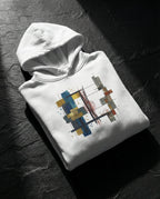 White Lazarus Hoodie folded on dark stone, showing gold, blue, grey and rust geometric artwork.