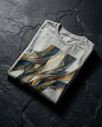 Athletic Heather Imputed Tee folded on dark stone, showing blue, charcoal and gold fracture artwork.
