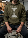 Man in a gritty industrial workshop wearing a Selah Supply Co Military Green 'Component: Temper' hoodie featuring a technical crystalline grain shatter graphic inspired by Ephesians 4:15.
