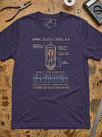 Heather Midnight Navy Glitch tee laid flat on a workbench, showing the tube filament, signal generator and voltage/flicker graph.