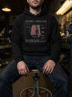 Model seated in a workshop wearing a black Intake hoodie with the red cutaway air-filter graphic.