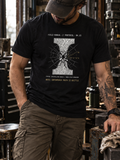 Front view of a standing model in a workshop, wearing a black heather T-shirt with a white I-shaped section with a shattered center and radiating fracture lines centered on the front.