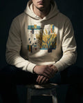 A model wearing a beige Nine 37 scripture hoodie in a dark, gritty mechanical workshop. The graphic visualizes that the harvest is plentiful but the workers are few, styled for a modern, conversation-starting Christian lifestyle