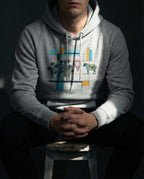 Model wearing the Carbon Grey One Percent hoodie, showing geometric sheep, blue and gold bars and a red scribble separating one sheep from the flock.