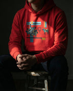 Model wearing the Team Red One Percent hoodie, showing geometric sheep, blue and gold bars and a red scribble separating one sheep from the flock.