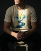 Model seated wearing the Natural Impossible Tee with a golden arch above a winding blue and gold river surrounded by clouds.