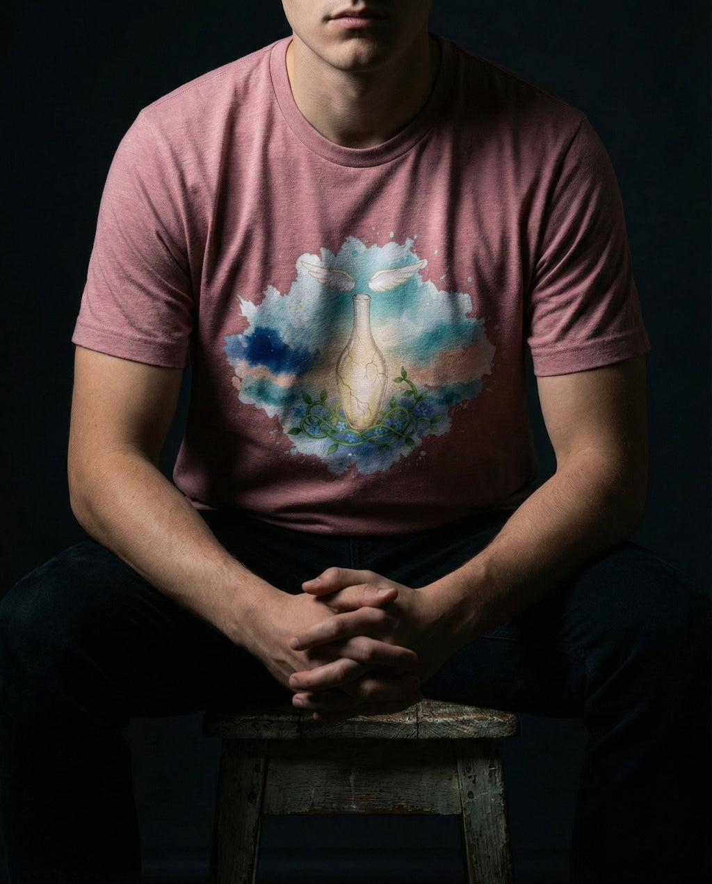 Selah Supply Co. The Thorn Tee in Heather Orchid. Model wearing a Christian graphic tee featuring the 'Cracked Vessel' glass vase with an internal glow and floral vines, symbolizing 2 Corinthians 12:9. Styled against a dark background.