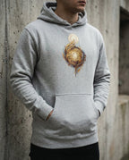 Model wearing the Carbon Grey Edify Hoodie with interwoven golden figures rising toward a light.