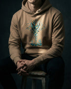 Model wearing the Latte Thirty Sixty Hundred Hoodie with a tall teal, navy and gold spray of seeds and leaves above small seedlings.