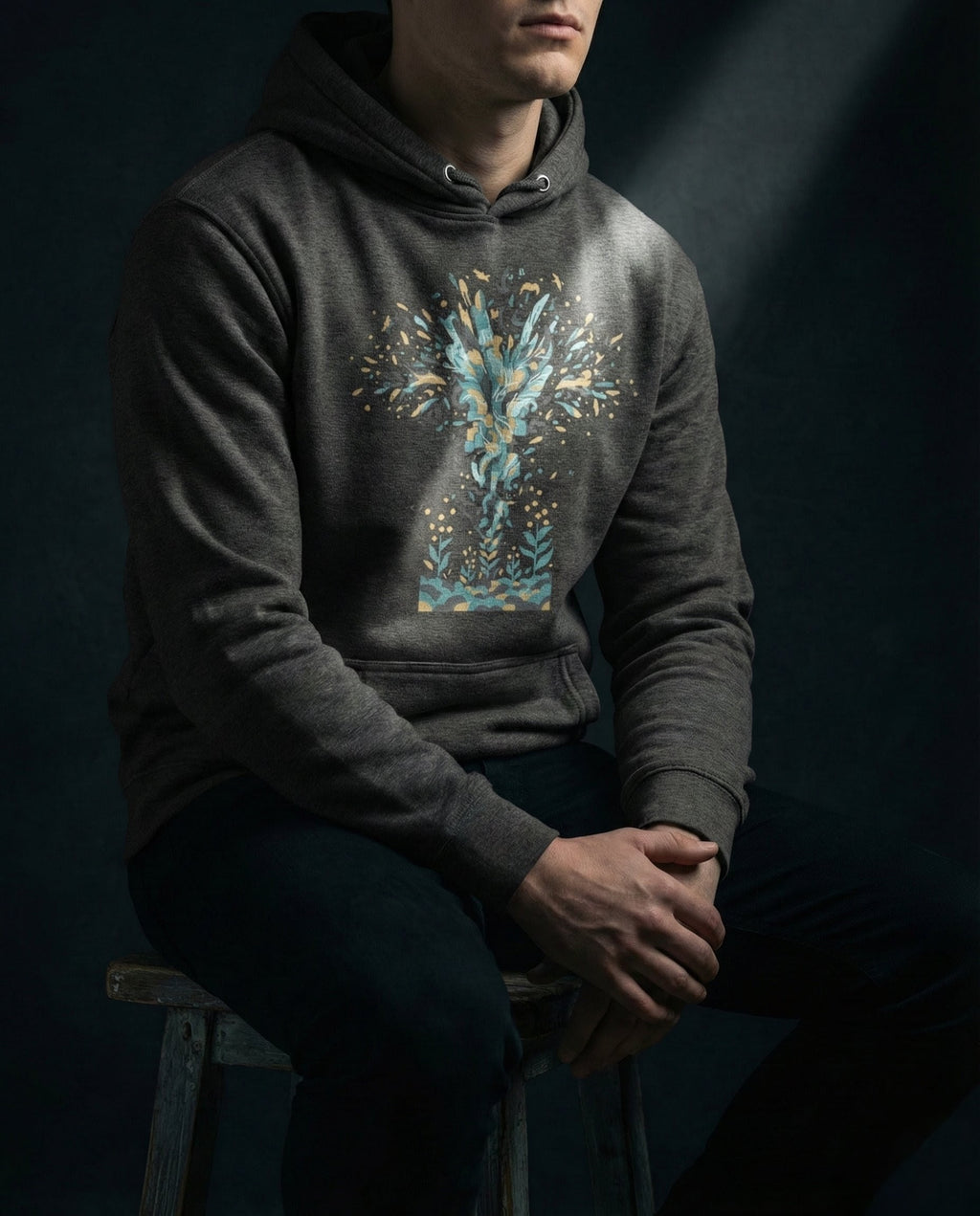 Selah Supply Co. The Thirty Sixty Hundred Hoodie in Charcoal Heather. Model wearing a Christian graphic hoodie that visualizes the Parable of the Sower through a massive burst of color representing the 'Indiscriminate Scattering' of the Word. Styled against a dark background.
