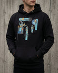 Person wearing a black hoodie with abstract design against a concrete wall