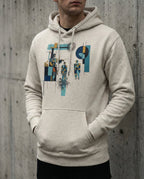 Model wearing the Oatmeal Heather Insolvent Hoodie with geometric creditor and debtor figures, stacked gold and tangled black lines.