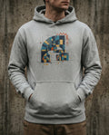 Selah Supply Co. The Secret Place Hoodie in Carbon Grey. Model wearing a Christian graphic hoodie that visualizes Psalm 91 through a blue and gold 'Geometric Arch' protecting a space of light from 'The Chaotic Scribble' of external threats.