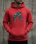 Red hoodie with geometric design worn by a person against a concrete wall.