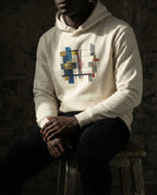 Model wearing the Bone Lazarus Hoodie with gold, blue, grey and rust geometric artwork.