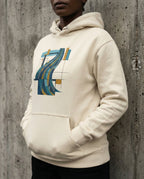 Model wearing the Bone Many Waters Hoodie with flowing blue, teal and gold bands crossing a black geometric grid on the front.