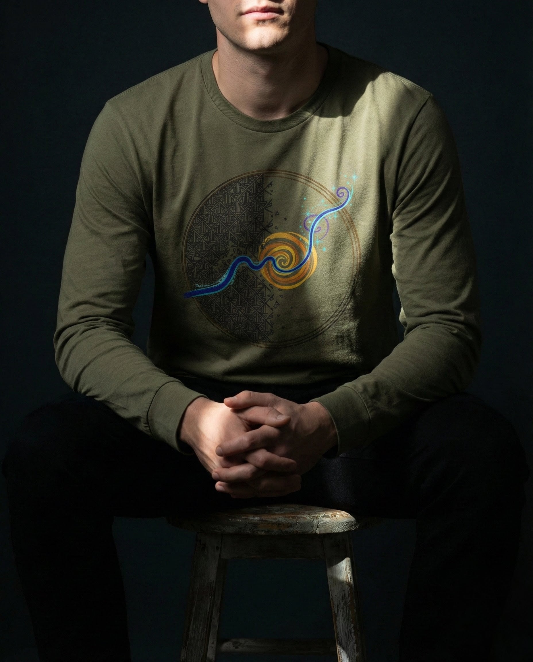 Person wearing a green long-sleeve shirt with a colorful design on a dark background