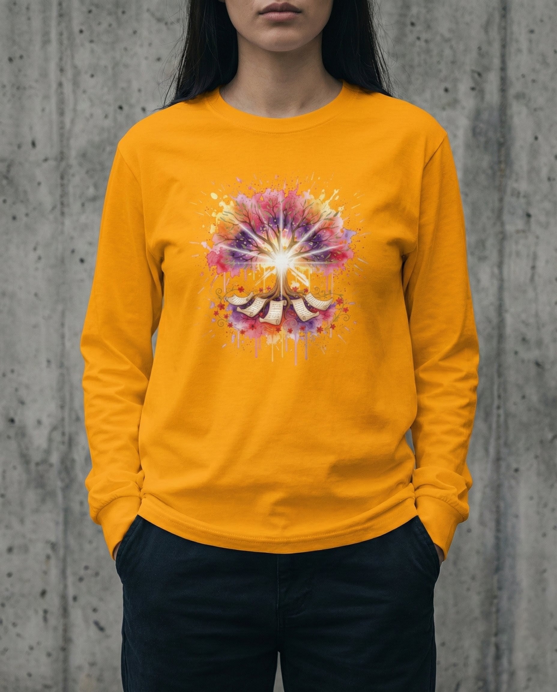 Person wearing a yellow long-sleeve shirt with a colorful design against a concrete wall.