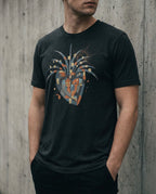 Model wearing the Black Heather East West Tee with a geometric heart, blue wing-like forms, gold squares and red and black scribbles.