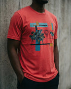 Model wearing the Heather Red One Percent tee, showing geometric sheep, blue and gold bars and a red scribble separating one sheep from the flock.