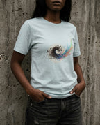 Model wearing a Heather Prism Ice Blue Former Things Tee with a dark swirl turning into teal, pink, yellow and blue printed on the front.