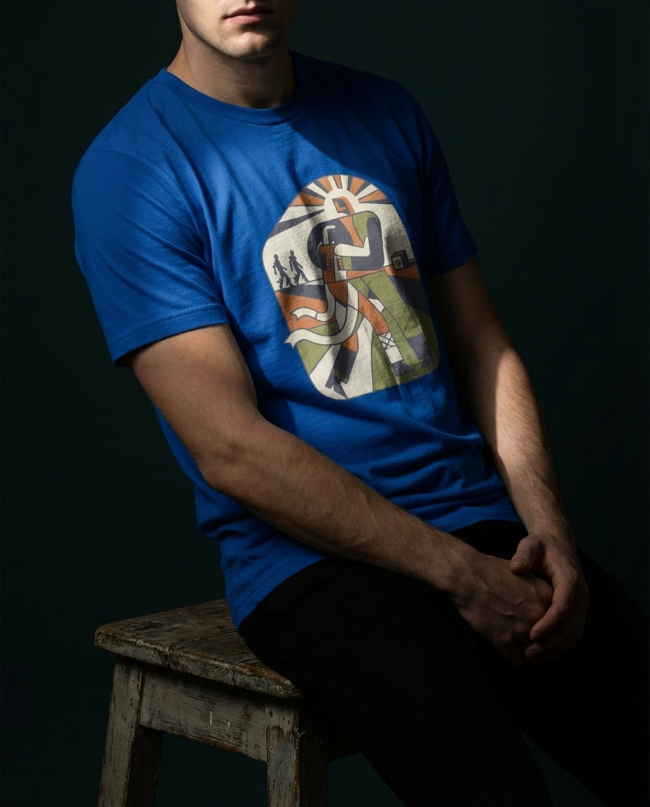 Person wearing a blue t-shirt with a graphic design, sitting on a wooden stool against a dark background
