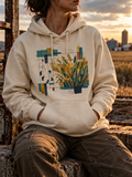 Model wearing the Bone Nine 37 Hoodie with gold wheat, small figures and geometric grid artwork.