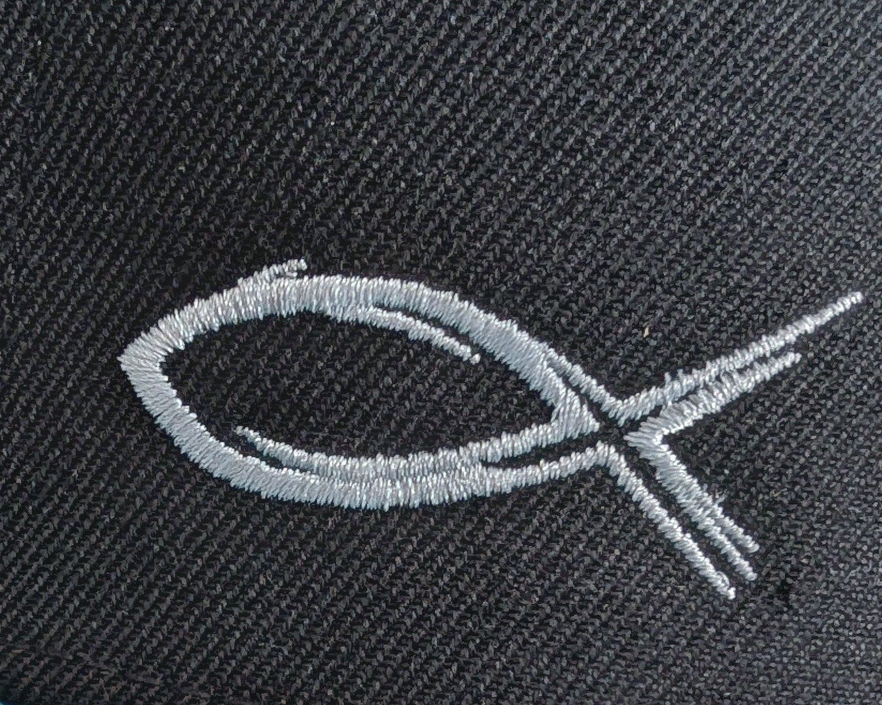 Embroidered fish symbol on a dark fabric background