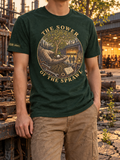 Model wearing a forest green T-shirt with THE SOWER OF THE SPRAWL around a circular illustration of a gloved hand holding seeds, a tree, exposed roots, and a workshop.