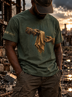 A man wearing an olive green graphic t-shirt with a distressed design of two hands holding a torn cloth, set against a ruined cityscape at sunset.