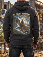 Back view of a charcoal heather hoodie with THE WHEELS & THE WATCHMAN above a figure sounding a trumpet from a stone tower, cascading water, ruins, and wheels.