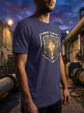 Front-facing vertical lookbook photograph of a model wearing a dark gray heather premium cotton t-shirt. The garment features a large, centered golden circular graphic emblem depicting a detailed mechanical micro-chip core layout. Clean focus on the chest print against a natural, sunlit outdoor background.