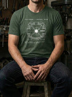 Model seated in a workshop wearing a Heather Forest Reaction tee with a chamber schematic and central burst of white light.