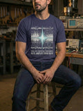 "A model wearing a navy scripture-based t-shirt in a mechanical workshop with electronics equipment and oscilloscopes. The industrial graphic design visualizes 'amplifying your faith' in a gritty, conversation-starting urban aesthetic."