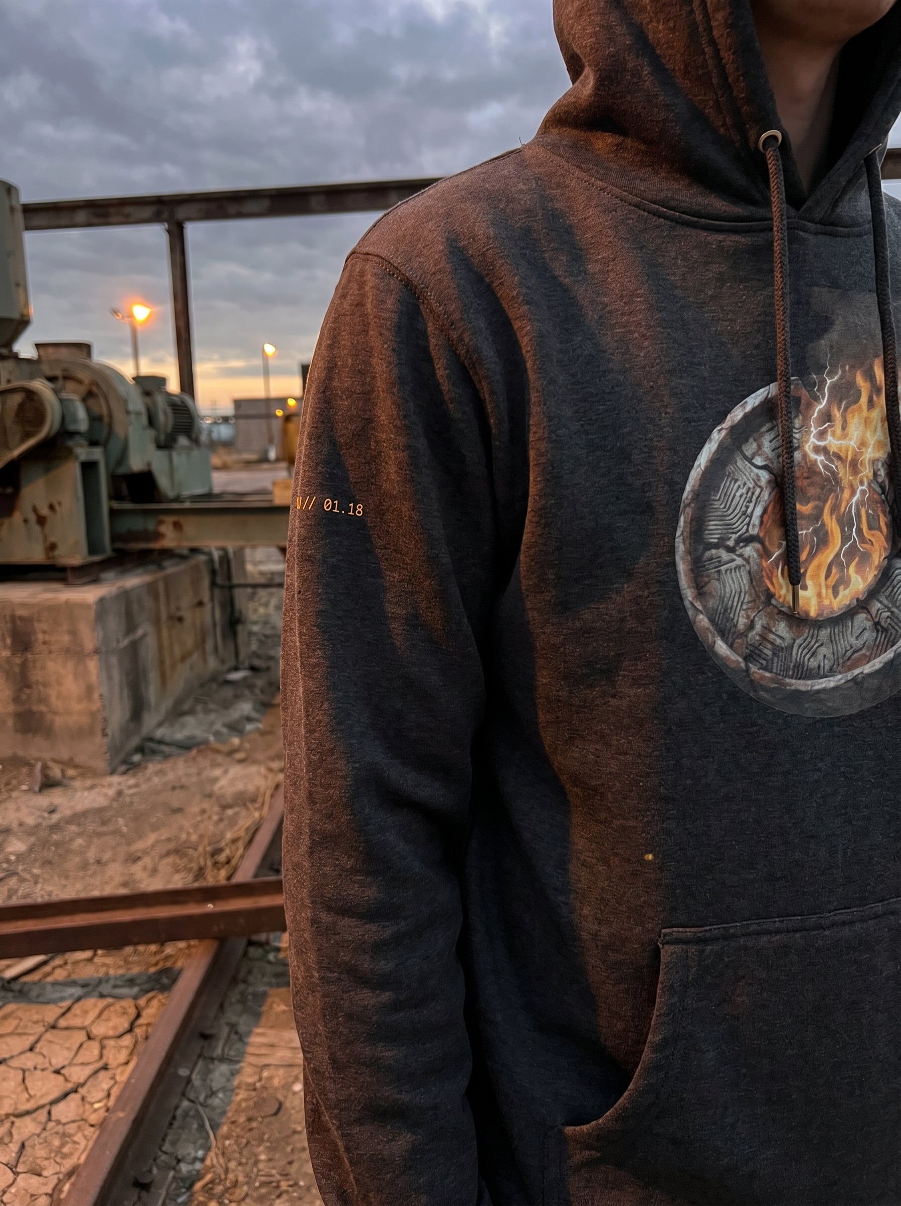 Model wearing the Selah Supply Co. Charcoal Heather Transmission: Firewall Falls // FREQ: 01.10 hoodie, showcasing the premium fabric fit and brutalist architectural art in an industrial concrete setting.
