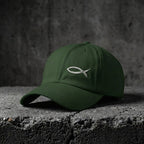 Spruce Sand Sketch Cap with light fish embroidery on concrete.