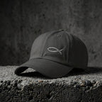 Dark grey Sand Sketch Cap with light fish embroidery on concrete.