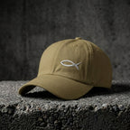 Khaki Sand Sketch Cap with light fish embroidery on concrete.