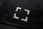 Close-up of four rough white embroidered corner marks framing an open square on black fabric.