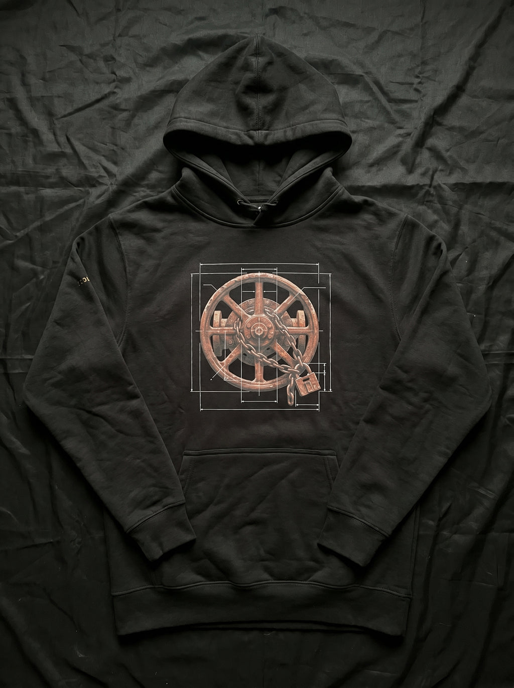An isolated product mockup of the premium black graphic hoodie. The layout cleanly showcases the high-contrast white technical line-work, architectural blueprint grid lines, and the centered weathered wheel with its interlocking chain and padlock design against the dark fabric.