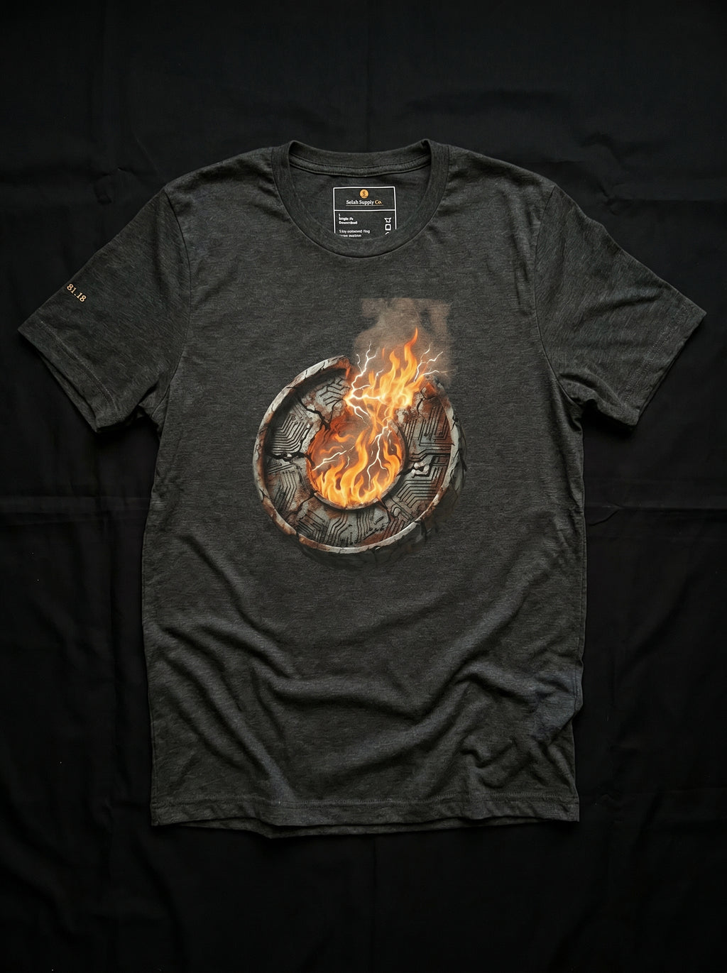 An isolated product flat-lay mockup of the premium black cotton t-shirt, laid completely flat against an absolute solid black background. The layout perfectly showcases the high-contrast, centered chest graphic of the burning metallic core emblem with sharp orange and white flame accents.