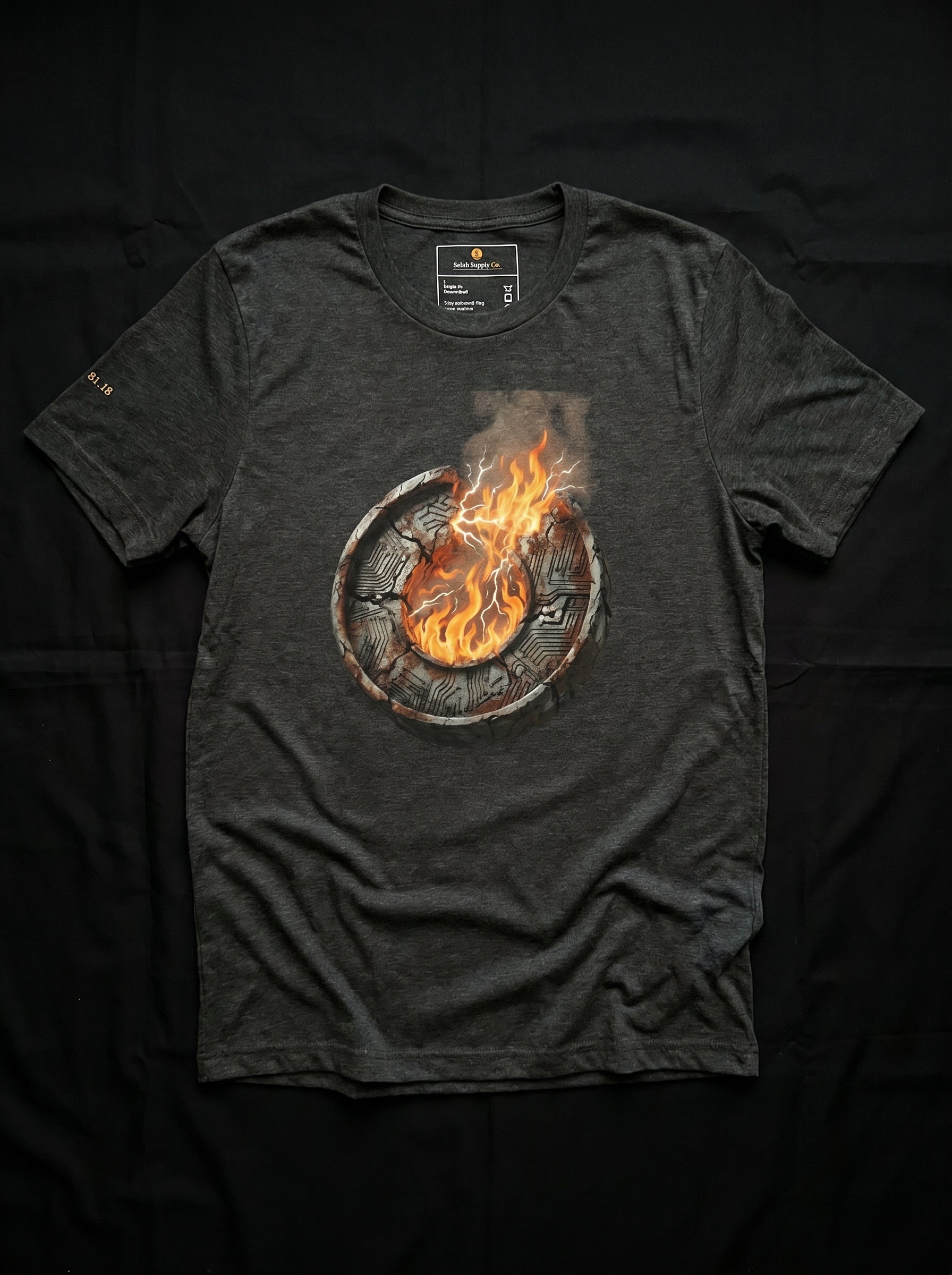 An isolated product flat-lay mockup of the premium black cotton t-shirt, laid completely flat against an absolute solid black background. The layout perfectly showcases the high-contrast, centered chest graphic of the burning metallic core emblem with sharp orange and white flame accents.